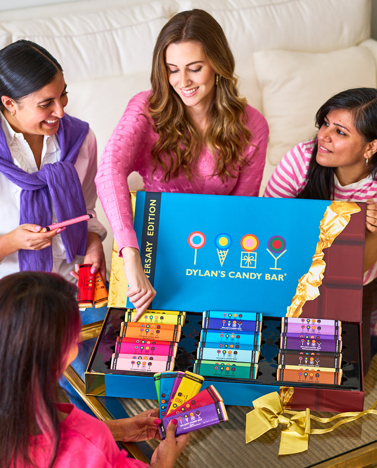 Four women around an open Anniversary Edition XL Chocolate Bar Gift Set that’s on top of a coffee table